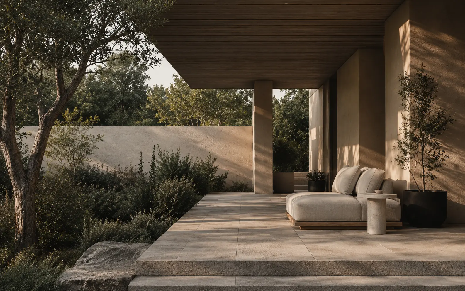 Sheltered stone terrace surrounded by mature landscaping and warm late-afternoon light.